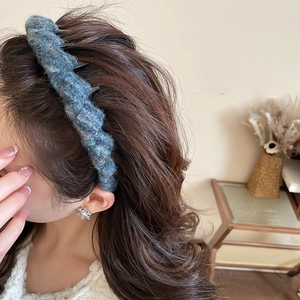 Detail showing knitted texture of a blue-grey acrylic wavy headband on female model