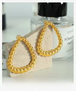 Detail view of large gold twisted rope hoop earrings with a textured teardrop design