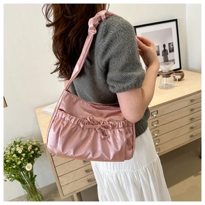 Détail d'un sac à bandoulière en satin rose avec design plissé et décoration en nœud