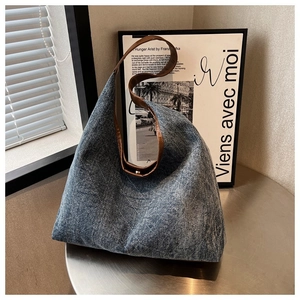 Detail of blue denim tote bag with brown leather strap on a small round table