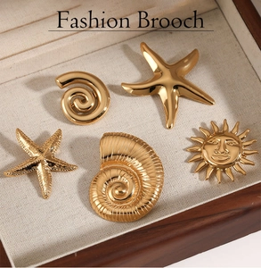 Set of gold nautical brooches with starfish and sun motifs on a velvet tray