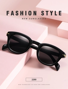 Detail of black small-frame sunglasses with gold arrow studs on pink geometric blocks