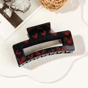 Detail view of rectangular black hair claw clip with vibrant red heart splatters