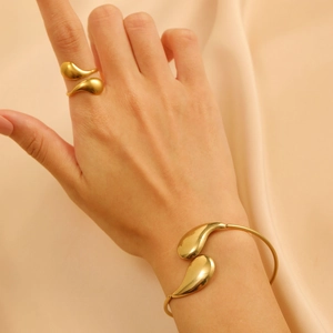 Luxurious gold stainless steel teardrop jewelry set with ring and bangle on silk fabric