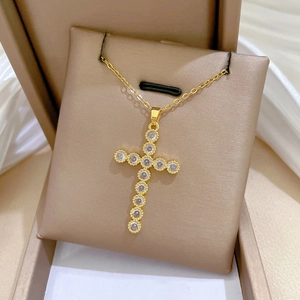 Detail of a gold-plated cross necklace with sparkling zircons on a luxury display