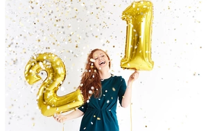 Golden 21 number foil balloons held by a smiling woman with festive falling confetti