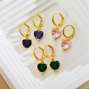 Detailed shot of three pairs of gold hoop earrings with purple, pink, and green heart charms