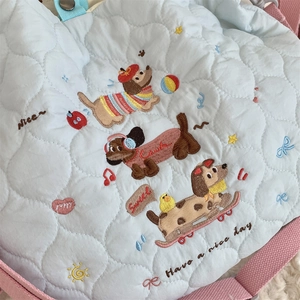 Close-up of cute cartoon dachshund embroidery and pink strap on light blue quilted bag