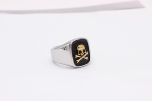 Detail of vintage men's ring with golden skull and crossbones on black rectangle