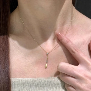 Macro detail of teardrop gold pendant necklace with cubic zirconia on model neck