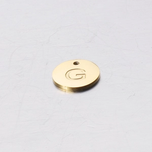 Macro view of gold stainless steel round charm with engraved letter G for DIY jewelry