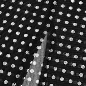 Detail of breathable black mesh fabric with white polka dot pattern and reinforced stitching