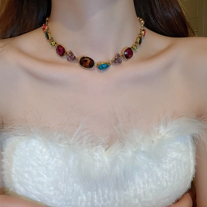 Close-up of vintage gold necklace with colorful teardrop pearls and crystals on a model