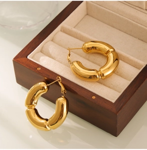 Detail view of gold-plated bamboo joint hoop earrings on a luxury wooden jewelry box