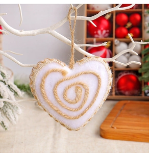 Gros plan d'un cœur en peluche blanc avec spirale en jute pour sapin