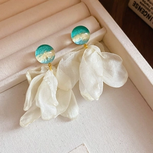 Detail of floral tassel earrings with blue gradient studs in a soft velvet jewelry box