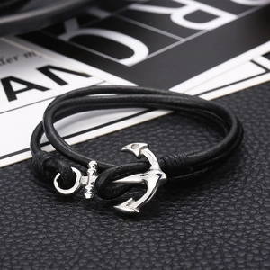 Macro shot of silver anchor clasp and black braided leather strap on textured background