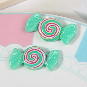 Detailed macro view of two green resin candy-shaped charms with colorful spiral patterns