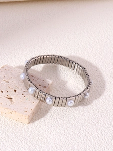Dettaglio di un bracciale elastico in acciaio inossidabile con perle bianche su pietra