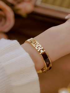 Close-up of a vintage gold chain watch bracelet with tortoise shell resin inlay on a wrist