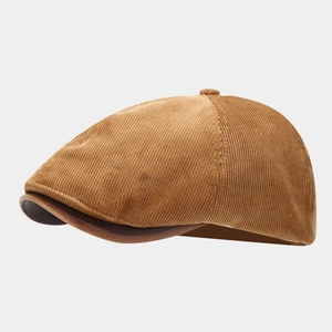 Close-up of mustard corduroy texture and brown faux leather brim on a vintage octagonal cap