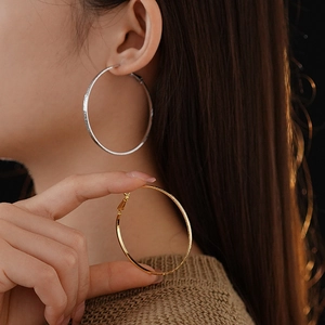 Detail of textured gold and silver hoop earrings shown on model for size and finish