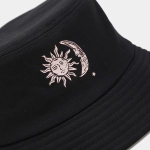 Detail of sun and moon embroidery on a black cotton twill bucket hat with high-quality texture