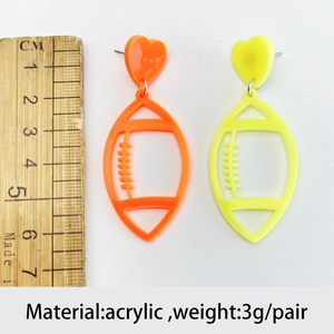 Macro shot of 7cm fluorescent acrylic heart football earrings with size reference ruler