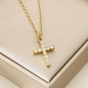 Close-up of golden cross pendant necklace with white rhinestones and a delicate O-chain