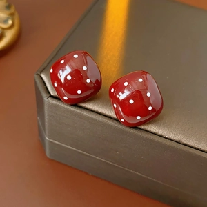 Detailansicht der roten quadratischen Polka-Dot-Ohrringe auf einer Geschenkbox mit warmem Licht