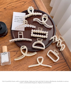 Detail shot of elegant gold-plated hair claws with white pearls on a wooden tray