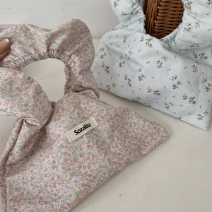 Detailed close-up of floral fabric handbags with stylish pleated handles in pink and blue