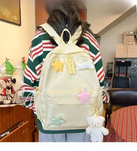 Detail of a cream yellow school backpack with star patches and cute white plush bear pendant