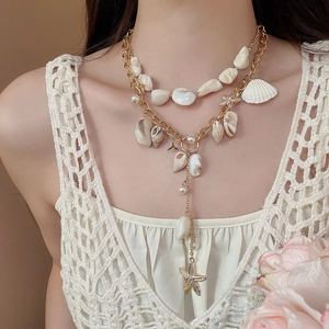 Detail of layered ocean necklace with gold chains, natural sea shells and white pearls