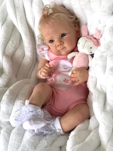Detail of 18 inch reborn baby doll with blonde hair, pink outfit and bunny plush toy