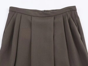 Detail of dark brown pleated skirt showing waist design, twill fabric, and hidden zipper