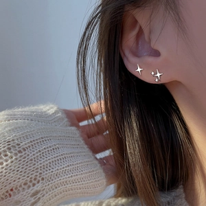 Asymmetric silver star stud earrings with single and triple star designs on model