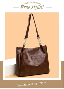 Detail of brown PU leather tote bag with unique patchwork texture and metal chain strap
