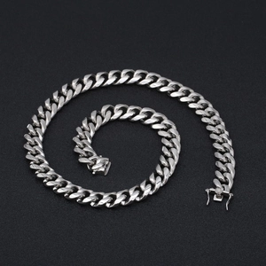 Detailed top view of a silver stainless steel Cuban link chain with box clasp on black background