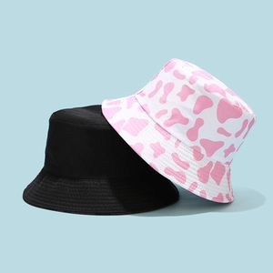 Dual-sided cotton bucket hat featuring solid black and pink cow print patterns
