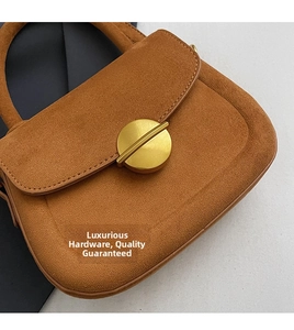 Close-up of brown suede handbag featuring a premium round gold metal buckle and stitching