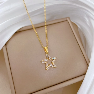 Detailed view of a gold hollow star pendant with clear crystals on a satin background