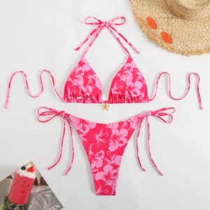 Close-up of pink tropical floral bikini with a gold pendant and adjustable side ties