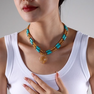 Close-up of double-layer turquoise bead necklace with a heart-shaped yellow stone pendant