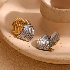 Detailed view of bicolor wave-textured earrings on a beige ceramic display tray