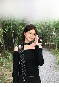 Détail d'un foulard noir à pois rétro noué sur un haut noir élégant à épaules dénudées