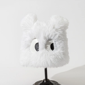 Close-up of white plush monster bucket hat with cute large eyes and soft fluffy ears