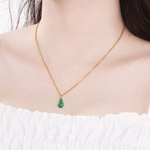 Close-up of a model wearing a gold necklace with a green textured avocado pendant