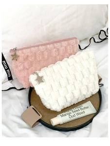 Detail of plush checkerboard cosmetic bags with silver star charms and soft woven texture