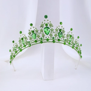 Detailed view of silver baroque tiara featuring emerald green crystals on white base